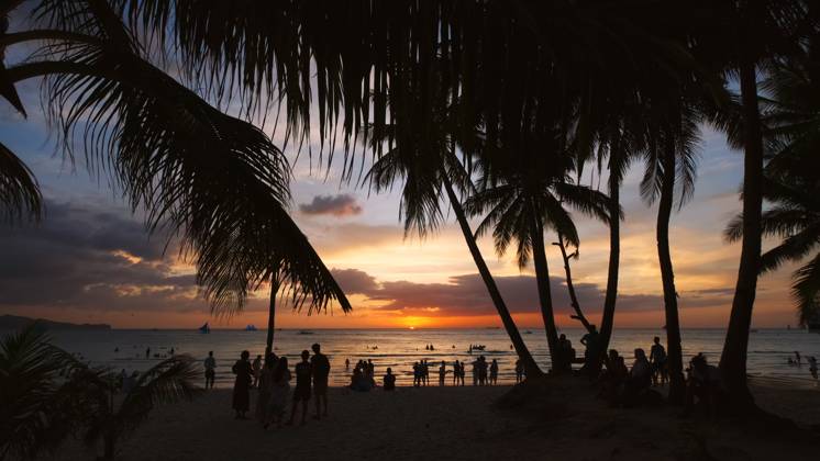 Sunset on beach with people and palms Silhouetted people and palms near sea. Sunset at tropical White beach, Boracay island, Philippines Copyright: xZoonar.com MikhailxKokhanchikovx 21445809