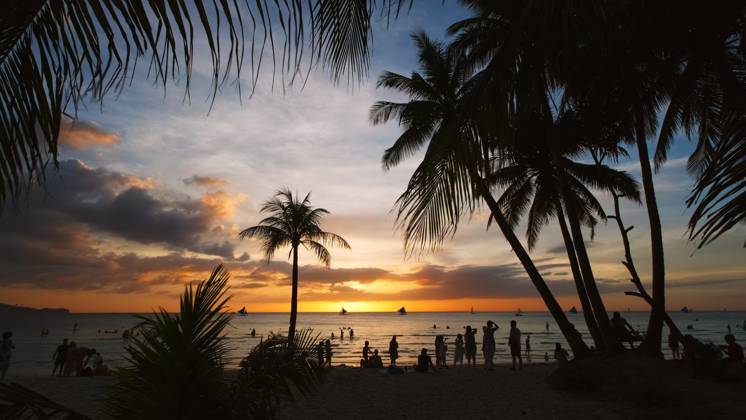 Sunset on beach with people and palms Silhouetted people and palms near sea. Sunset at tropical White beach, Boracay island, Philippines Copyright: xZoonar.com MikhailxKokhanchikovx 21445814