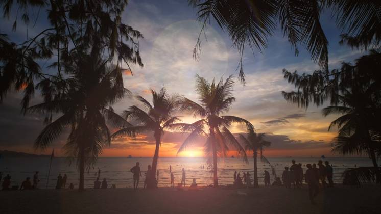 Sunset on beach with people and palms Silhouetted people and palms near sea. Sunset at tropical White beach, Boracay island, Philippines Copyright: xZoonar.com MikhailxKokhanchikovx 21482136