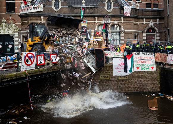 Bilder des Jahres 2024, News 05 Mai News Themen der Woche KW19 News Bilder des Tages AMSTERDAM - A police shovel throws rubble from the barricades into a canal near the Binnengasthuis grounds of the University of Amsterdam (UvA). Entrances to the site were blocked from several sides with, among other things, pallets and bicycle racks. The demonstrators were protesting in solidarity with pro-Palestinian students who were removed by police during protests at the Roeterseiland campus. ANP RAMON VAN FLYMEN netherlands out - belgium out  Copyright: xx x497953741x originalFilename: 497953741.jpg