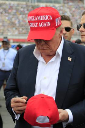 CHARLOTTE, NC - MAY 26: Former President of the United States of America Donald Trump signs an autograph for a fan on pit road prior to the running of the NASCAR Cup Series Coca-Cola 600 on May 26, 2024 at Charlotte Motor Speedway in Charlotte, NC. (Photo by Jeff Robinson Icon Sportswire) EDITORIAL USE ONLY Icon1045686854