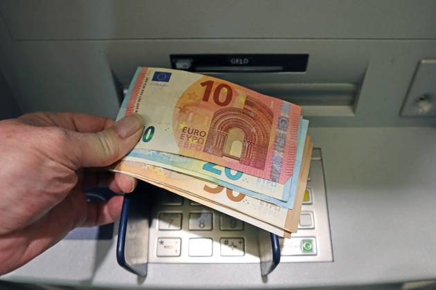 Bargeldversorgung aus einem Automat Eine Person holt an einem Geldautomaten eine größere Menge Bargeld in 50,20 und 10 Euro Geldscheinen ab