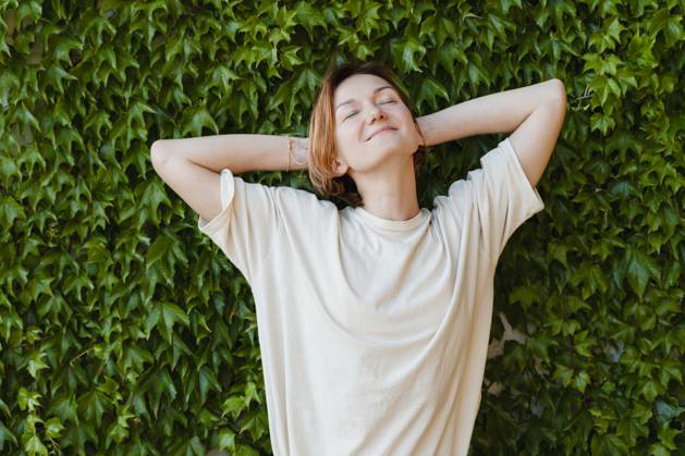 Smiling woman with hands behind head relaxing on plants model released, Symbolfoto, NDEF01870