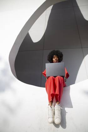 Freelancer using laptop and sitting on white wall of modern building model released, Symbolfoto, PCLF01101