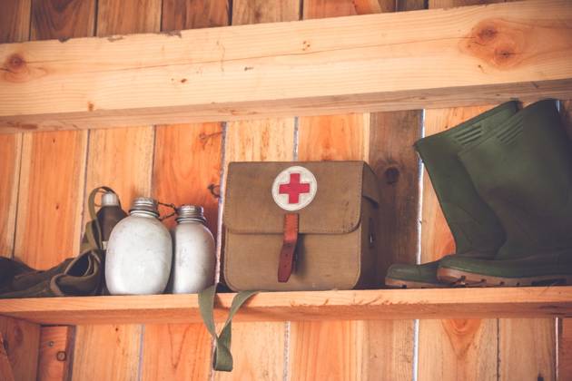 Retro medic equipment on an old wooden shelfe with boots and water bottles ,model released, Symbolfoto