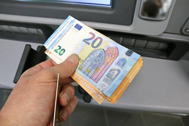 Bargeldversorgung aus einem Automat Eine Person holt an einem Geldautomaten eine größere Menge Bargeld in 50 und 20 Euro Geldscheinen ab