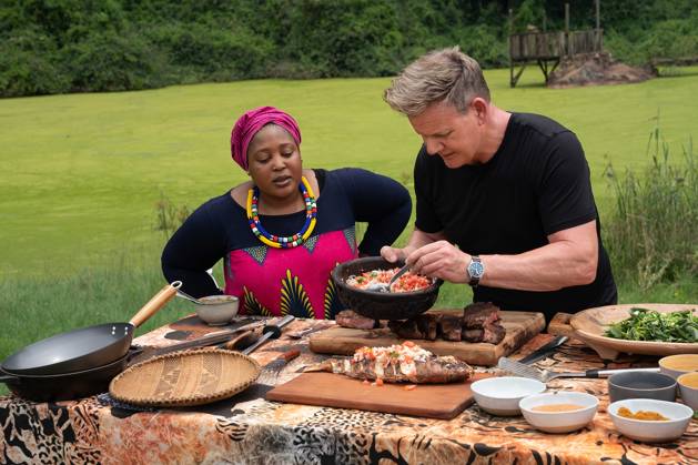Gordon Ramsay: Uncharted (2019) - filmstill South Africa - Chef Zola Nene (L) observes as Gordon Ramsay tops grilled fish with ushatini, a combination of onions and tomatoes. Gordon Ramsay: Uncharted (2019) EDITORIAL USE ONLY Copyright: xJonxKrollx