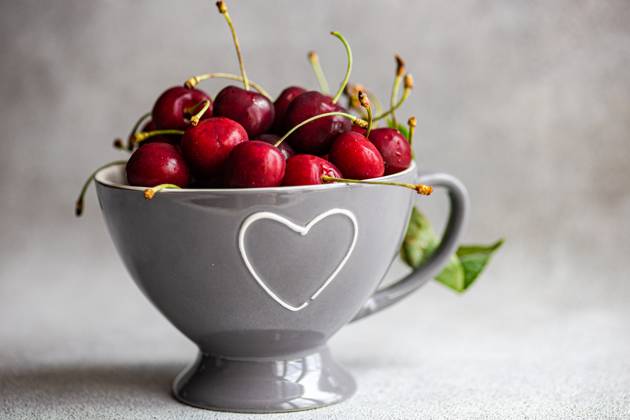 IMAGO Creative, Jahreszeit Sommer, Kirschen Ripe red cherries in a modern grey bowl with a heart-shaped cutout, placed on a textured grey background. The image captures the vibrant color and freshness of the cherries, suitable for culinary and lifestyle themes. Model Released AnnaBogush_ID22658_660688_007 Copyright: xAnnaxBogushx