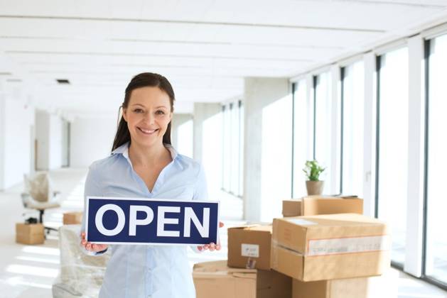 Portrait of smiling businesswoman holding open sign in new office ,model released, Symbolfoto