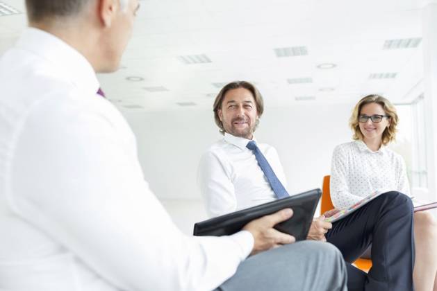 Smiling colleagues looking at businessman while sitting in new office during meeting ,model released, Symbolfoto