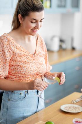 culinary and people concept - happy smiling young woman making cocktail drinks at home kitchen. woman making cocktail drinks at home kitchen ,model released, Symbolfoto