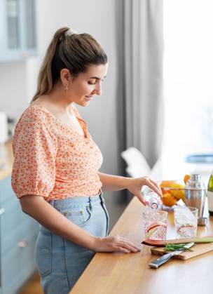 culinary and people concept - happy smiling young woman making cocktail drinks at home kitchen. woman making cocktail drinks at home kitchen ,model released, Symbolfoto
