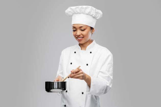 culinary and people concept - happy smiling female chef in toque and jacket with saucepan cooking food over grey background. happy smiling female chef with saucepan ,model released, Symbolfoto