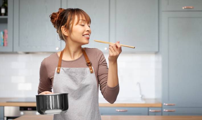 culinary and people concept - happy smiling woman in apron with saucepan cooking food over kitchen background. happy woman in apron with saucepan in kitchen ,model released, Symbolfoto