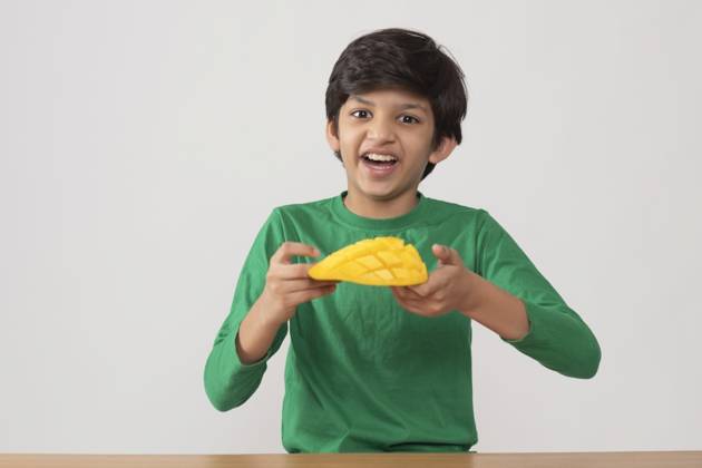 Portrait of happy boy holding a segmented slice of mango ,model released, Symbolfoto