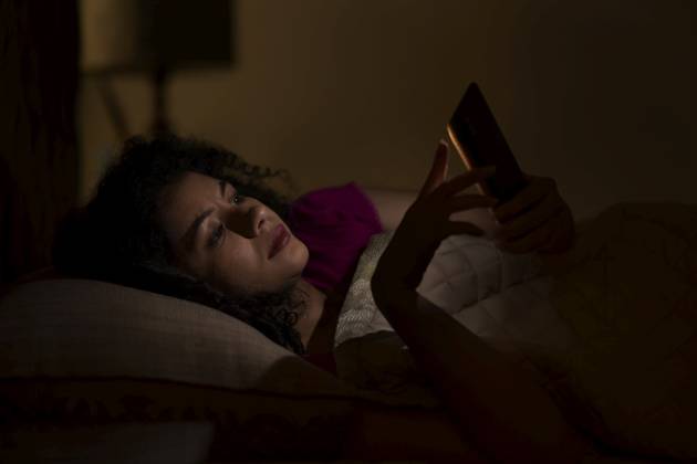 Woman Chatting on smartphone at night while lying on bed ,model released, Symbolfoto