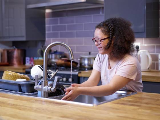 Girl with Down syndrome washing hands in kitchen sink model released Copyright: xCulturaxCreativex