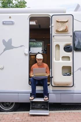 Freelancer using laptop and sitting on doorway of motor home model released, Symbolfoto property released, JCMF02415