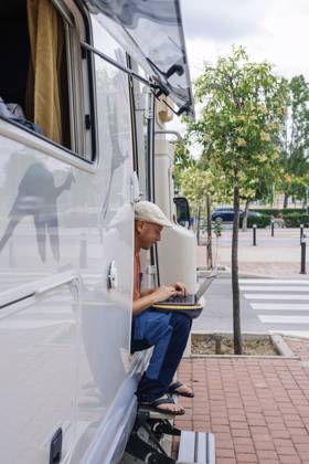 Freelancer using laptop and sitting on doorway of motor home near sidewalk model released, Symbolfoto property released, JCMF02416