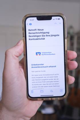 Betrügerische Phishing email auf einem Mobiltelefon die eine angebliche Aktivität bei einem Konto der Volksbanken Raiffeisenbanken meldet meldet