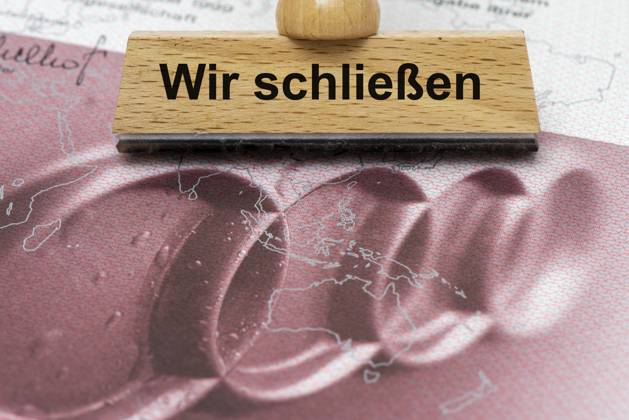 AUDI-Krise mit Gefahr der Werksschließung Ein Holzstempel ist beschriftet mit dem Aufdruck: Wir schließen, über einer AUDI-Aktie - Symbolbild