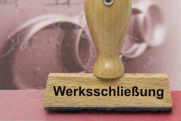AUDI-Krise mit Gefahr der Werksschließung Ein Holzstempel ist beschriftet mit dem Aufdruck: Werksschließung, über einer AUDI-Aktie - Symbolbild