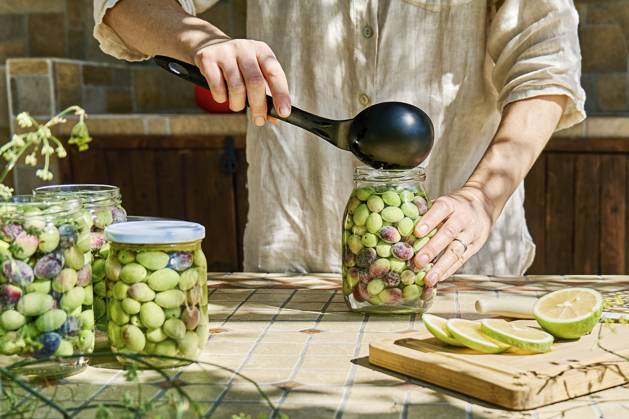 Mature woman preparing fermented olives in glass jar model released, Symbolfoto property released, CATF00449