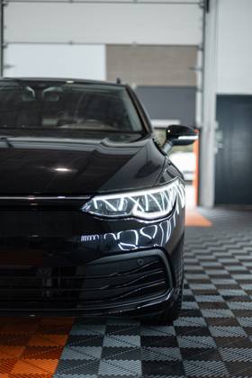 Schwarzes Auto mit optischen Scheinwerfern steht in der Garage. Autowäsche. Aufarbeitung. Reparatur
