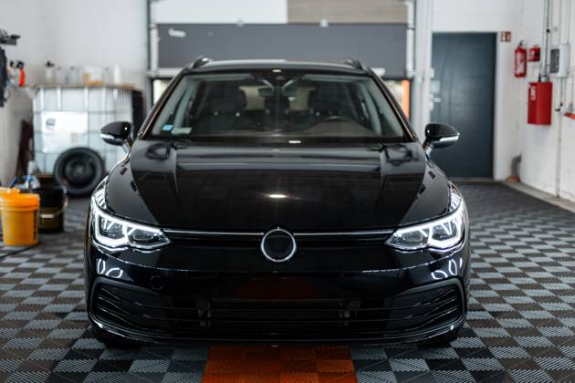 Schwarzes Auto mit optischen Scheinwerfern steht in der Garage. Autowäsche. Aufarbeitung. Reparatur