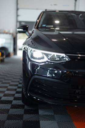 Schwarzes Auto mit optischen Scheinwerfern steht in der Garage. Autowäsche. Aufarbeitung. Reparatur
