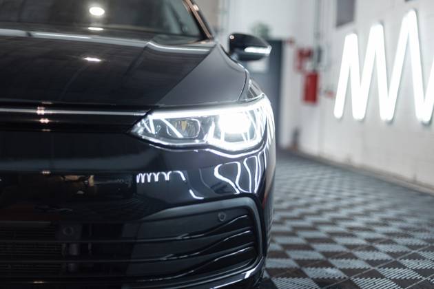 Schwarzes Auto mit optischen Scheinwerfern steht in der Garage. Autowäsche. Aufarbeitung. Reparatur