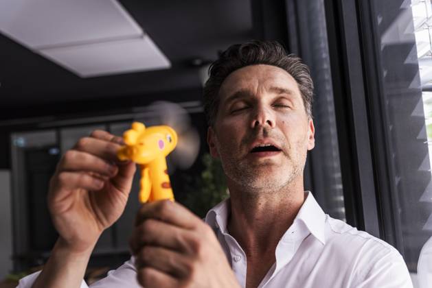 IMAGO Creative, Jahreszeit Sommer, Hitze Businessman using hand fan on face in office model released, Symbolfoto property released, UUF33640