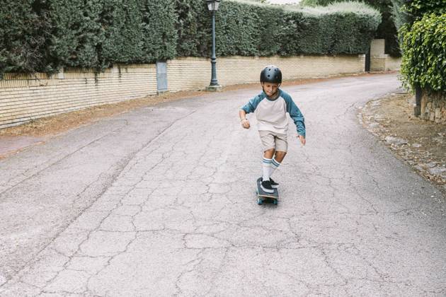 A young boy wearing a helmet rides a skateboard down a quiet suburban street The image captures the essence of childhood adventure and outdoor fun Model Released DavidBenito_ID25114_727152_016 Copyright: xDavidxBenitox RECORD DATE NOT STATED