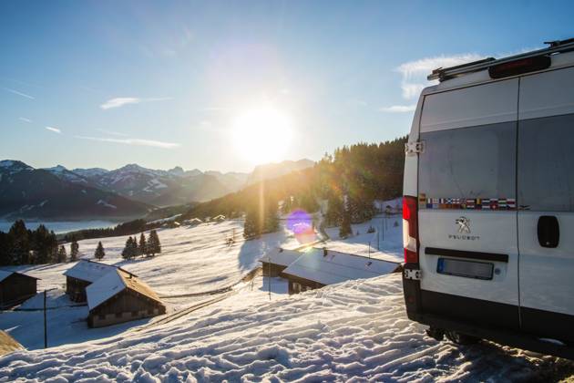 Ein Camper steht im Winter auf einem Parkplatz in den Alpen bei Sonnenaufgang im Schnee. Bödele, Vorarlberg, Österreich Winter in den österreichischen Alpen