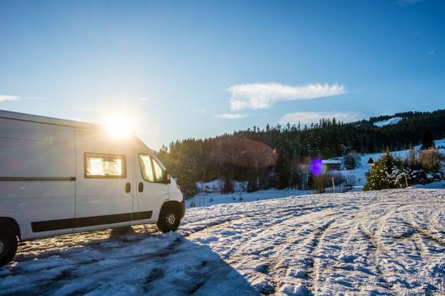 Ein Camper steht im Winter auf einem Parkplatz in den Alpen bei Sonnenaufgang im Schnee. Bödele, Vorarlberg, Österreich Winter in den österreichischen Alpen