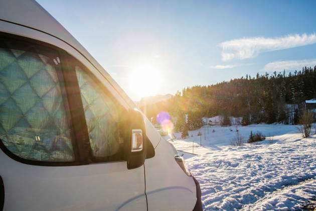 Ein Camper steht im Winter auf einem Parkplatz in den Alpen bei Sonnenaufgang im Schnee. Bödele, Vorarlberg, Österreich Winter in den österreichischen Alpen