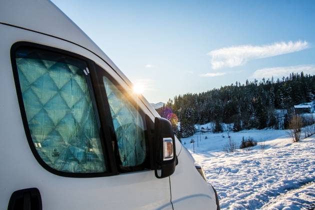 Ein Camper steht im Winter auf einem Parkplatz in den Alpen bei Sonnenaufgang im Schnee. Bödele, Vorarlberg, Österreich Winter in den österreichischen Alpen