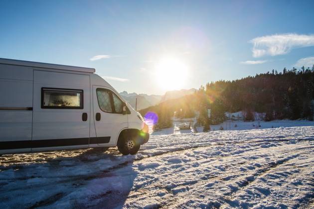 Ein Camper steht im Winter auf einem Parkplatz in den Alpen bei Sonnenaufgang im Schnee. Bödele, Vorarlberg, Österreich Winter in den österreichischen Alpen