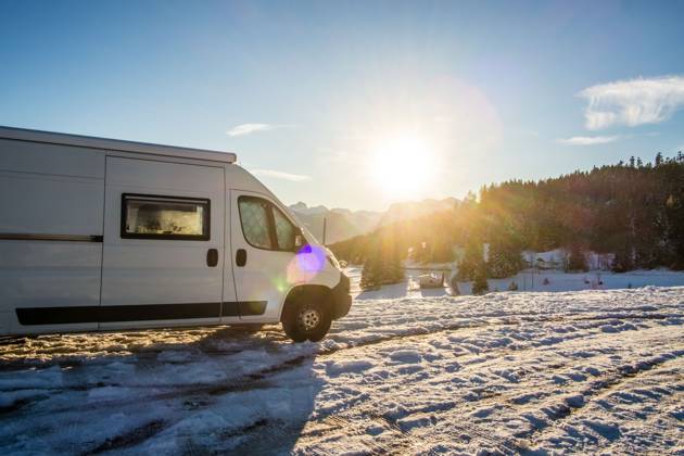 Ein Camper steht im Winter auf einem Parkplatz in den Alpen bei Sonnenaufgang im Schnee. Bödele, Vorarlberg, Österreich Winter in den österreichischen Alpen