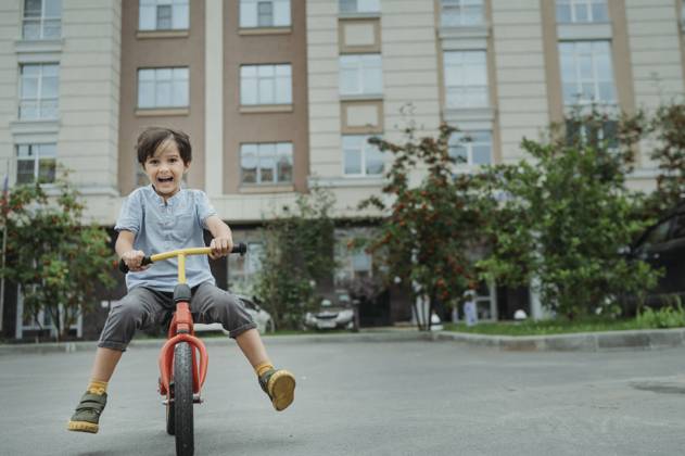 Happy boy riding bicycle in front of building model released, Symbolfoto, ANAF04287