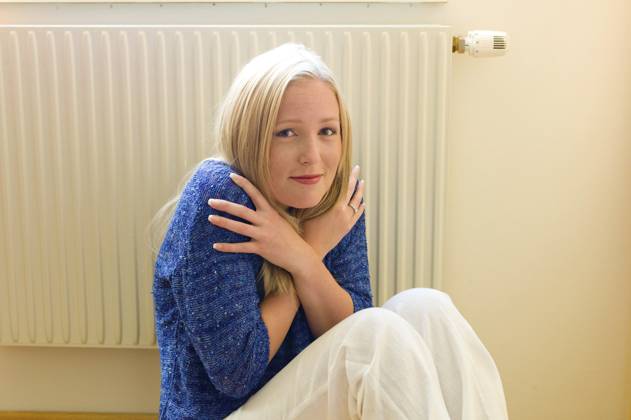 Eine junge Frau sitzt im Winter vor einem Heizkörper. Raumtemperatur ist zu niedrig. Austria A young woman sits in front of a radiator in winter. The room temperature is too low. Austria Copyright: imageBROKER ErwinxWodicka ibxiqx12050943.jpg ,model released, Symbolfoto ,property released
