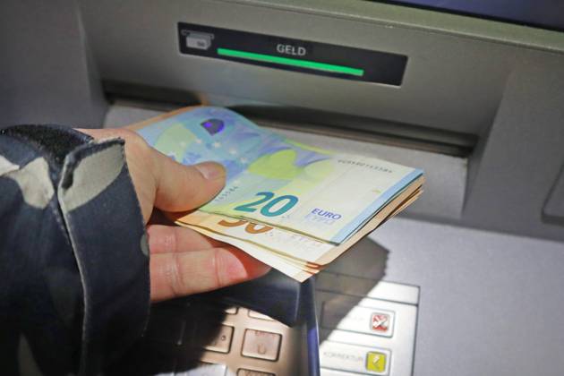 Bargeldversorgung aus einem Automat Eine Person holt an einem Geldautomaten Bargeld in 50 und 20 Euro Geldscheinen ab
