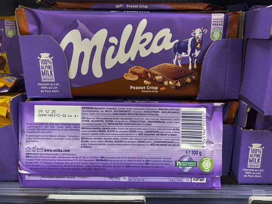 Symbolfoto - Milka Schokolade - 2 Tafeln Milka Alpenmich Schoholade mit dem jetzigen Geicht von 100 g im Regal beim Supermarkt in lilla Papier gehült mit dem Logo der Milka Kuh. Der Name ist eine Kombination der beiden Hauptzutaten Milch und Kakao. Der Kakaopreis steigt und steigt. Und das macht unsere geliebte Schoggi teurer Der US-Produzent Mondelez verkleinert zahlreiche Sorten.Drastische Preiserhöhung bei einer der bekanntesten Schokoladen-Marken Verbraucherinnen und Verbraucher müssen für Schokolade der bekannten Marke Milka derzeit vielerorts tiefer in die Tasche greifen Mondelez International ist ein börsennotierter US-amerikanischer Lebensmittelkonzern mit Sitz in Chicago, Illinois, der überwiegend auf Markenprodukte in den