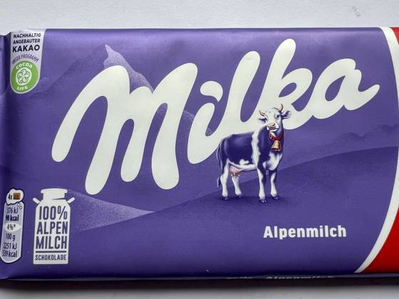 Symbolfoto - Milka Schokolade - Das Milka Logo mit der Lilla Kuh beim Supermarkt Discounter in lilla Papier gehült mit dem Logo der Milka Kuh. Der Name ist eine Kombination der beiden Hauptzutaten Milch und Kakao. Der Kakaopreis steigt und steigt. Und das macht unsere geliebte Schoggi teurer Der US-Produzent Mondelez verkleinert zahlreiche Sorten.Drastische Preiserhöhung bei einer der bekanntesten Schokoladen-Marken Verbraucherinnen und Verbraucher müssen für Schokolade der bekannten Marke Milka derzeit vielerorts tiefer in die Tasche greifen Mondelez International ist ein börsennotierter US-amerikanischer Lebensmittelkonzern mit Sitz in Chicago, Illinois, der überwiegend auf Markenprodukte in den Bereichen Snacks und Süßwaren spez