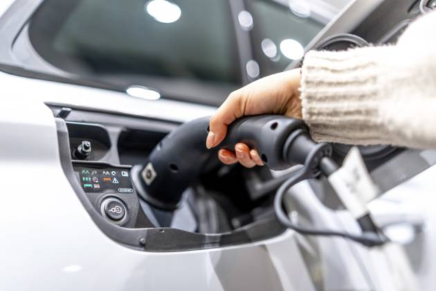 Nahaufnahme einer Hand, die in einem Autohaus ein Ladekabel an ein Elektrofahrzeug anschließt, um den Übergang zu nachhaltigen Verkehrsmitteln zu verdeutlichen Close up of a hand plugging a charging cable into an electric vehicle at a car dealership, showcasing the transition to sustainable transportation Copyright: imageBROKER UnaixHuizi ibxuhu12460362.jpg ,model released, Symbolfoto ,property released