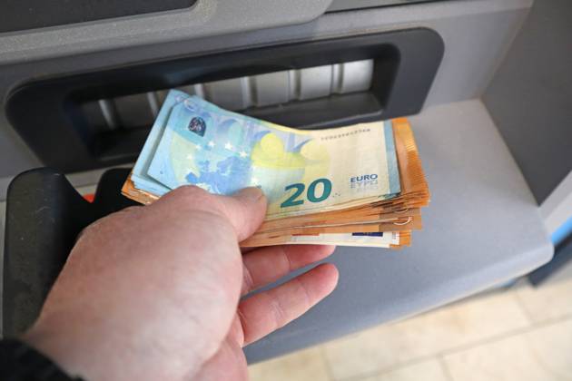 Bargeldversorgung aus einem Automat Eine Person holt an einem Geldautomaten Bargeld in 50 und 20 Euro Geldscheinen ab