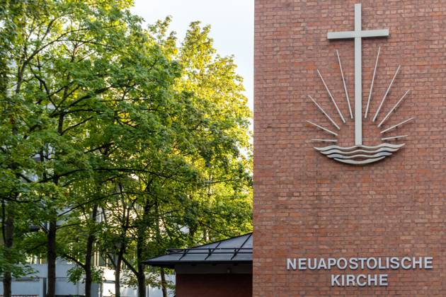 Fassade der Neuapostolischen Kirche in Augsburg mit modernem Kreuz-Symbol und rotem Klinker