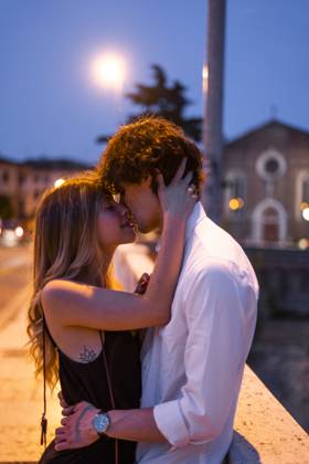 Affectionate young couple kissing inon a bridge at night, Verona, Italy model released, Symbolfoto, GIOF07024