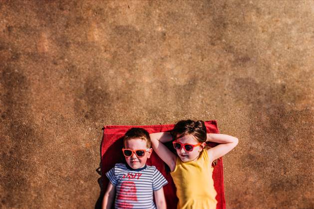 IMAGO Creative, Jahreszeit Sommer, Sommerferien Two kids laying on a towel in the sunshine with sunglasses Tulsa, Oklahoma, United States CR_KRRY250412-1661740-01 ,model released, Symbolfoto