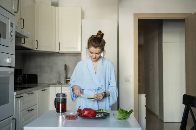 MR_ID27929_20617_TatyanaRangulova.jpg, PR_ID27929_10891_Cat.jpg, PR_ID27929_10892_Room.jpg A woman in a blue robe, slicing vegetables for a healthy meal in her modern kitchen. Fresh ingredients and a peaceful atmosphere highlight a relaxing home routine., Property released Model Released LiliyaSolopova_ID27929_802059_005 Copyright: xLiliyaxSolopovax